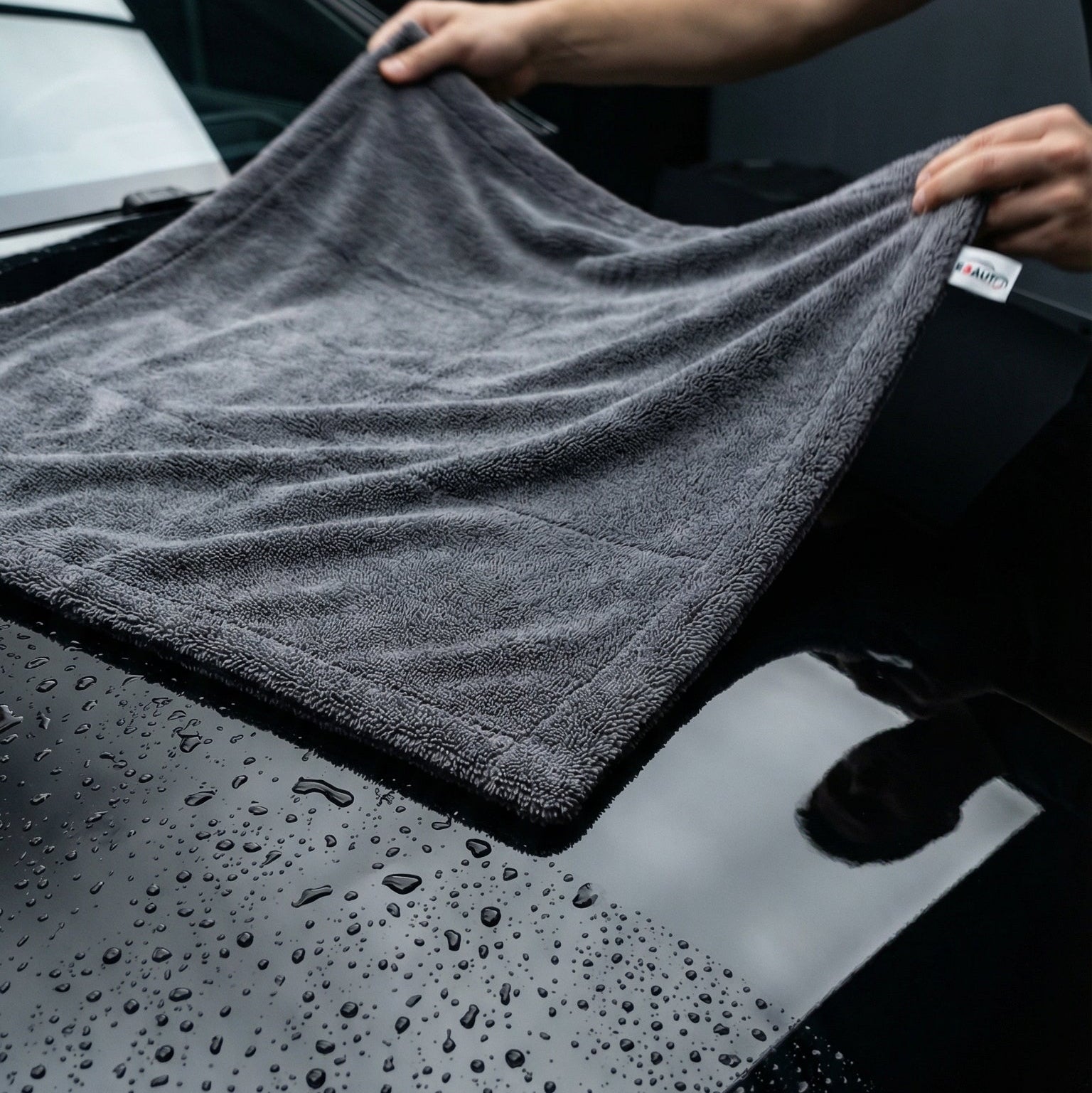 Serviette Manta E3AUTO 1400 GSM en action - séchage capot voiture noire en un seul passage sans traces ni micro-rayures